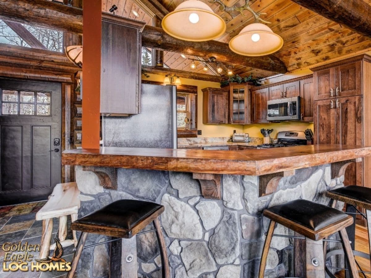 view over stone bar into kitchen with large lights over bar