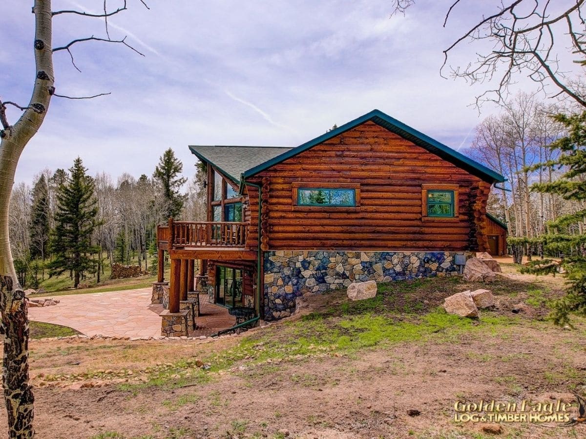 side of log cabin with stone foundation on hill