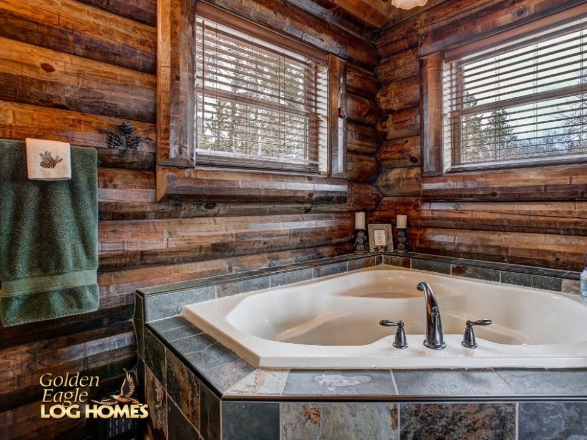 white soaking tub surrounded by gray tile