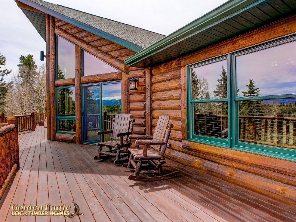 back deck on log cabin with green trim around windows