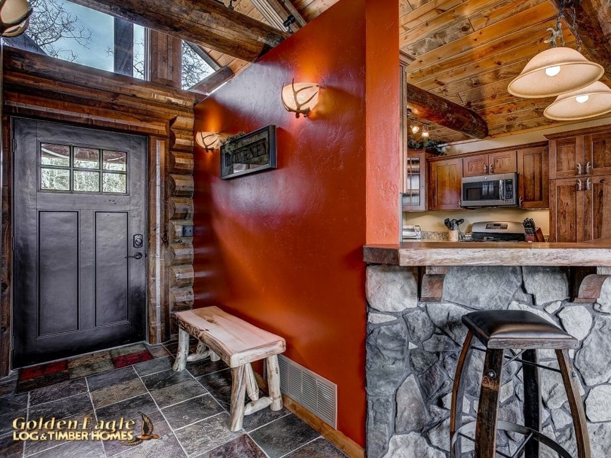 burnt orange wall in entryway of log cabin by stone wall