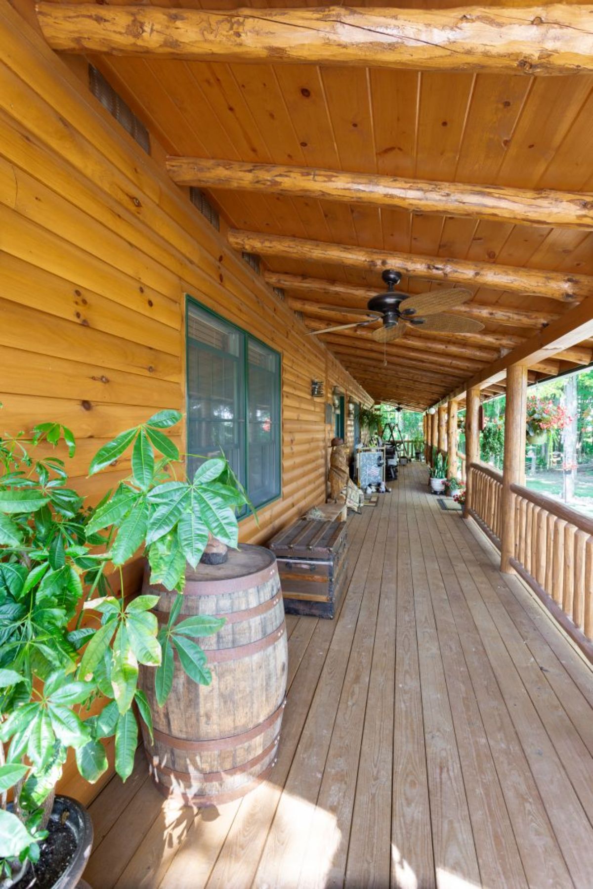 long porch on log cabin with potted plants on both sides of door