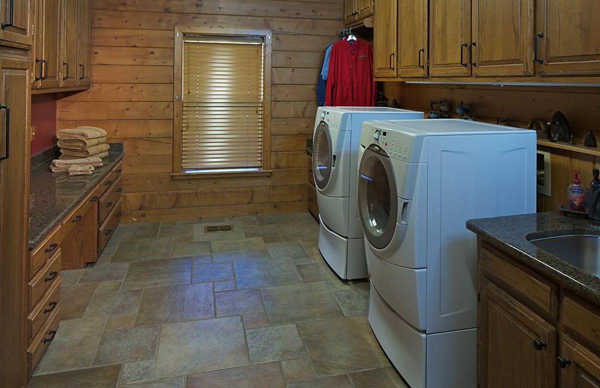 white washer and dryer against wall underneath light wood cabinets