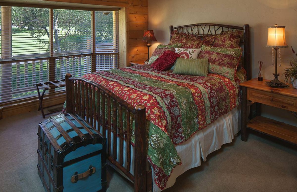 bed with colorful quilt next to french doors leading to balcony