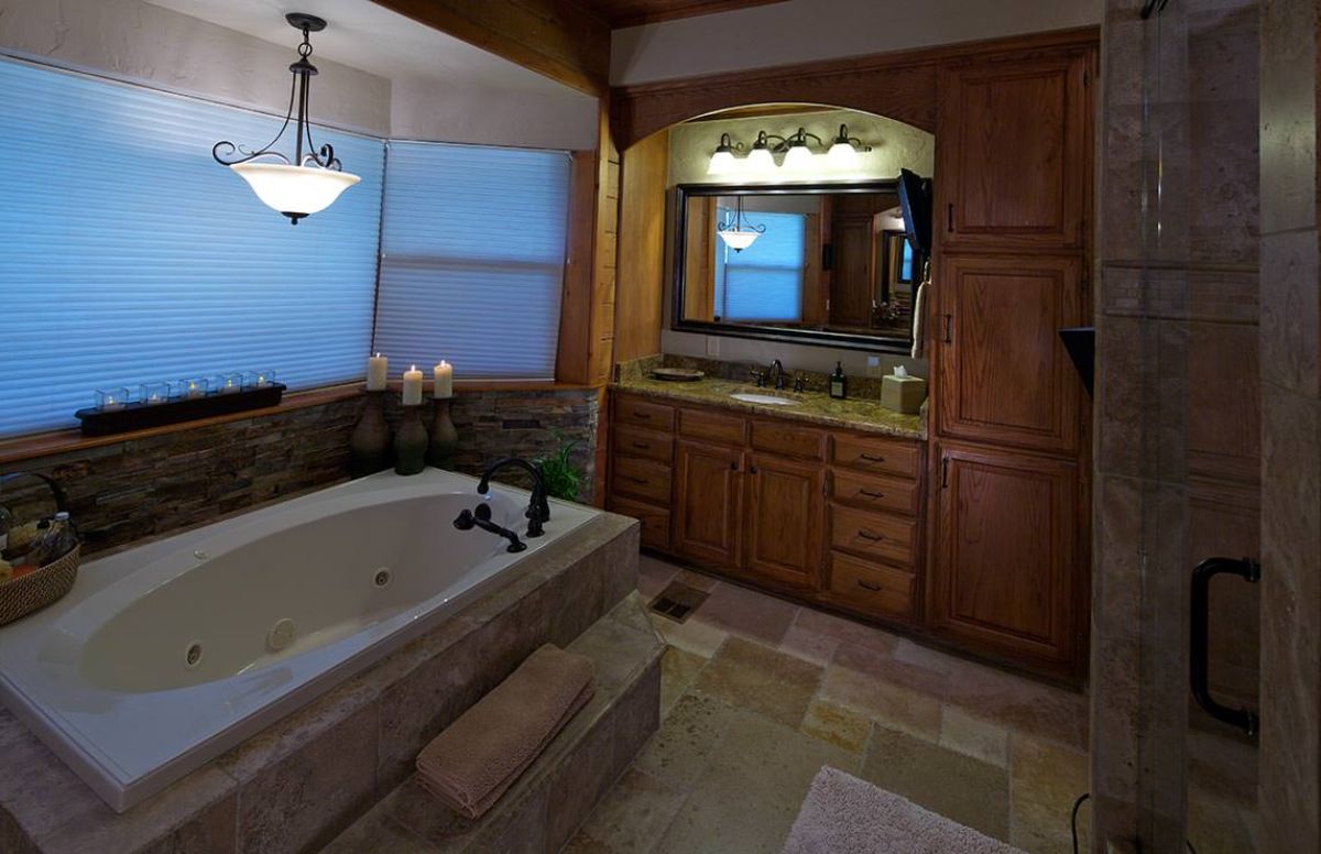 white soaking tub against wall of windows in bathroom with wall of cabinets