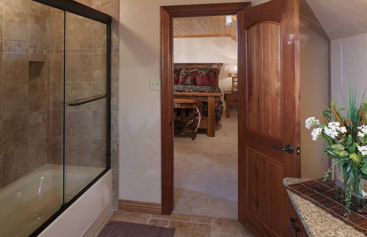 dark wood bathroom door open with bathtub shower combo on the left of image