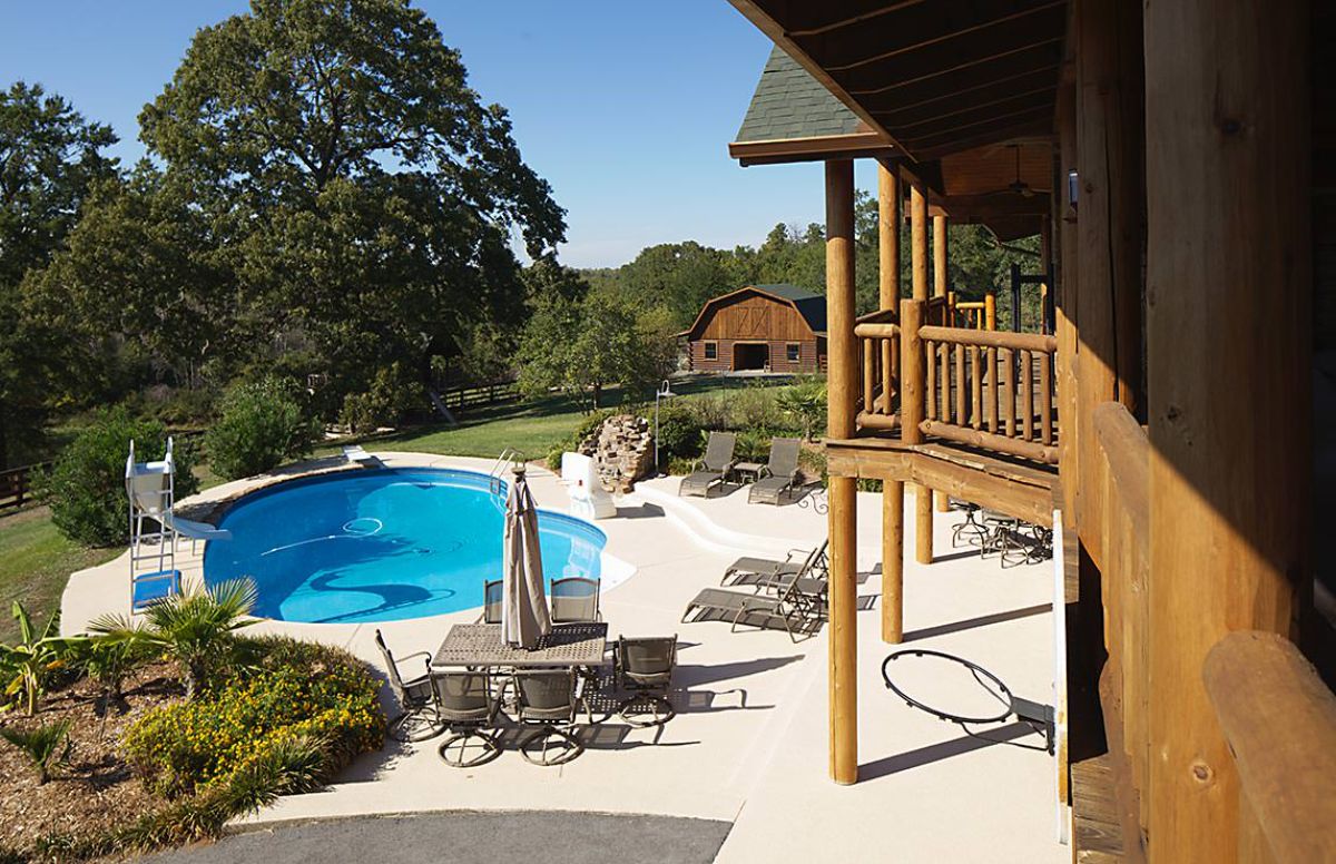 pool behind log cabin with concrete patio