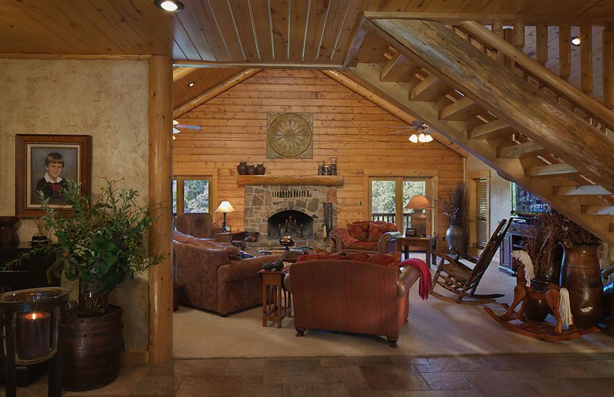 maroon sofas in log cabin with stone fireplace across front wall