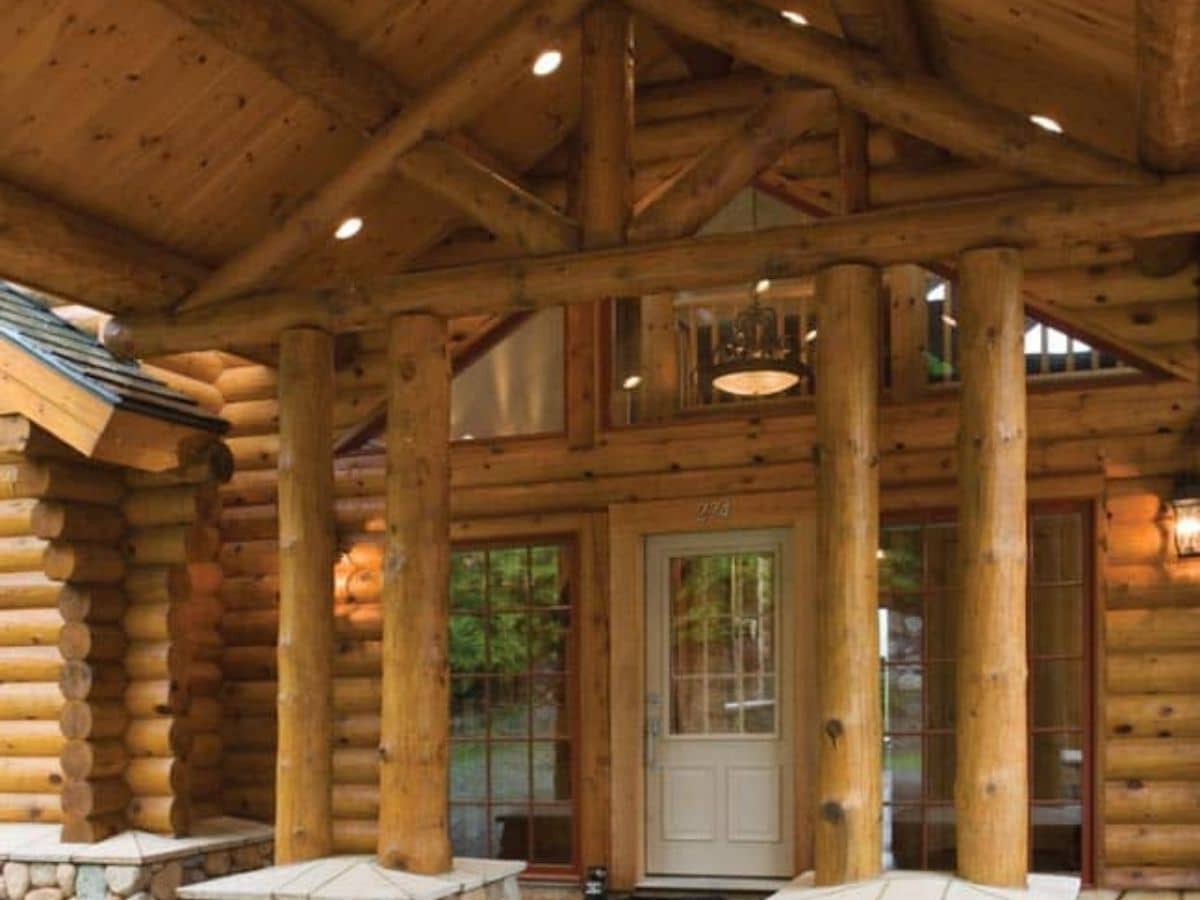 white front door to log cabin with log columns on all sides