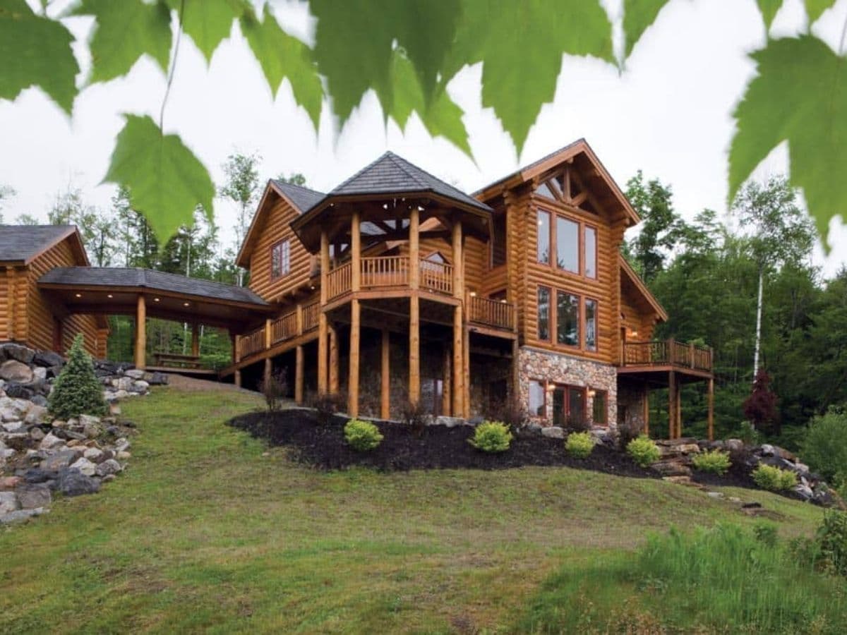 back side of log cabin on hill with dark mulch landscaping around log columns