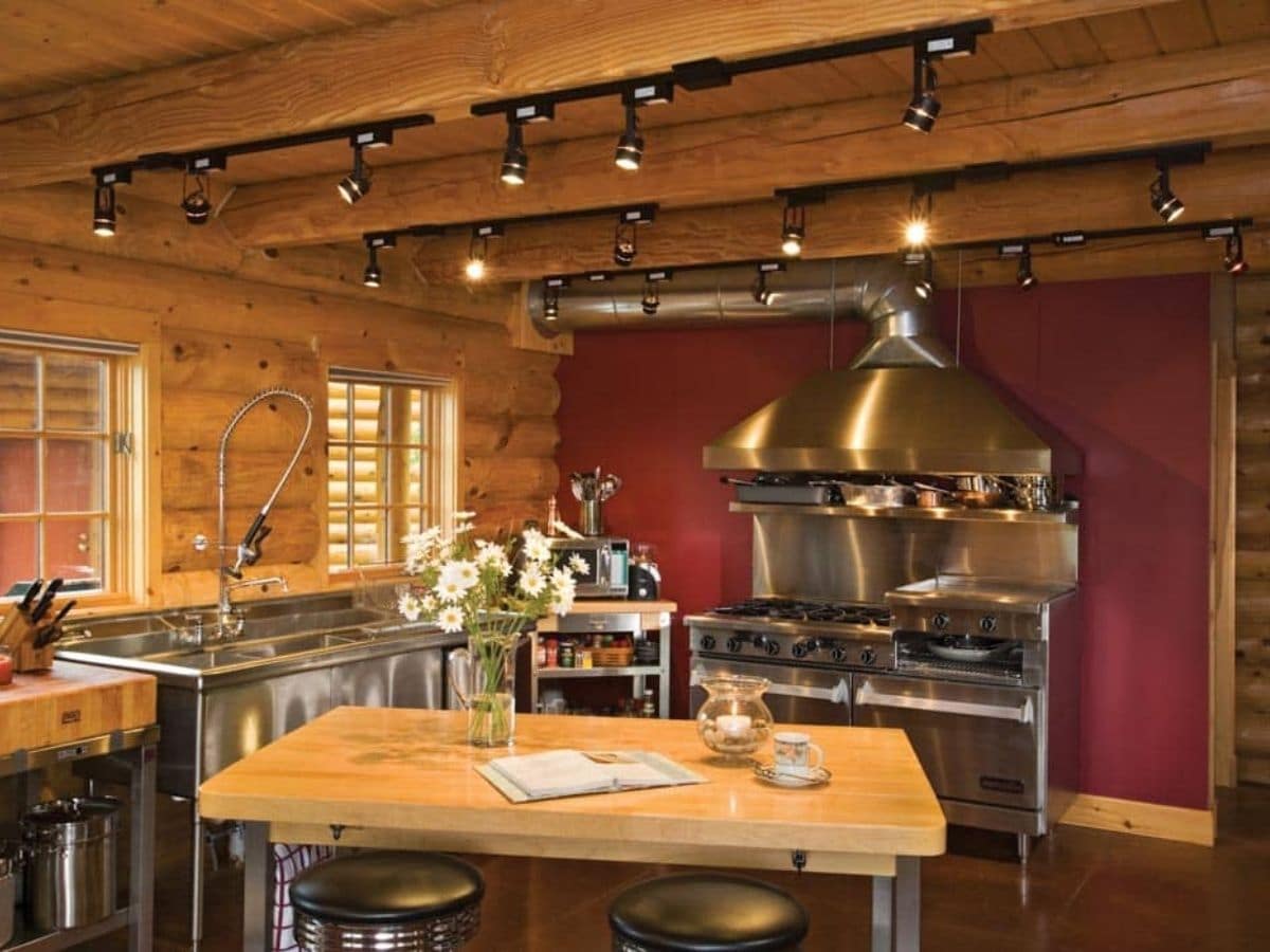 chef kitchen with stainless steel stove and wood countertops against red wall