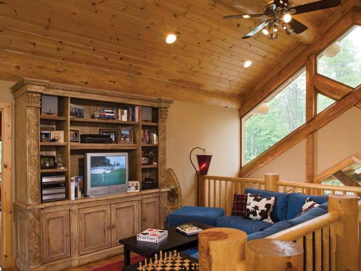 loft with blue chairs and entertainment center with TV against wall