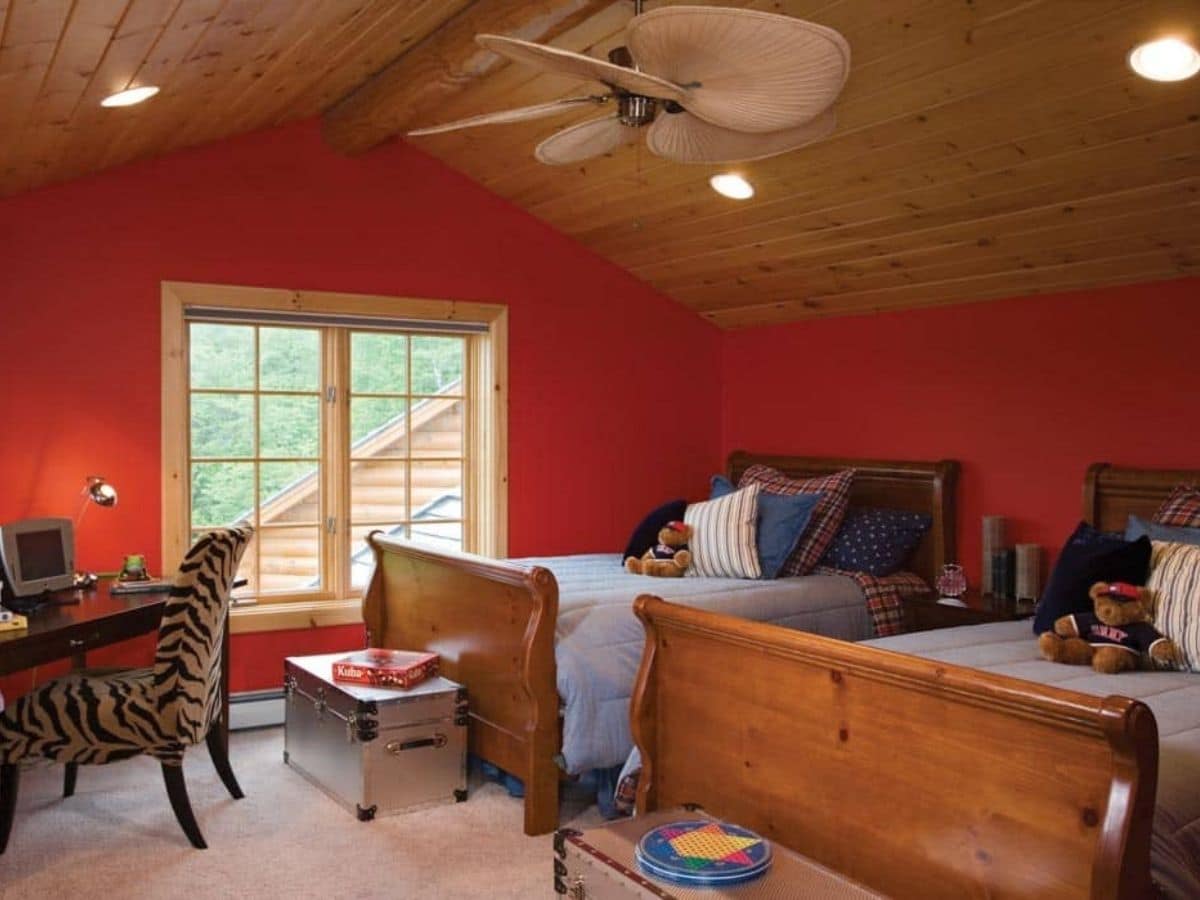 red wall in bedroom with two beds that have wood footboards