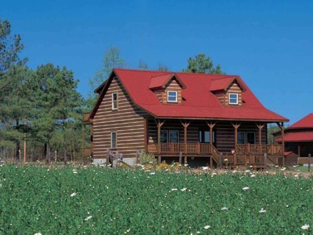 log cabin with red roof in green field