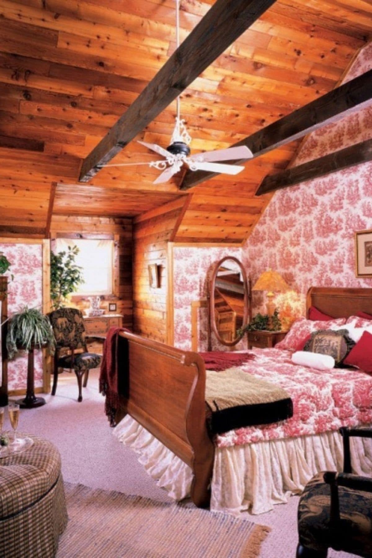 log cabin bedroom with light pink wallpaper and bedding on sleigh bed