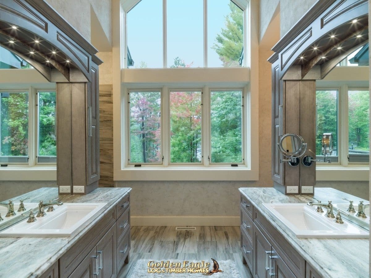 gray cabinets with white marble counter tops in bathroom with large white windows at back of bathroom