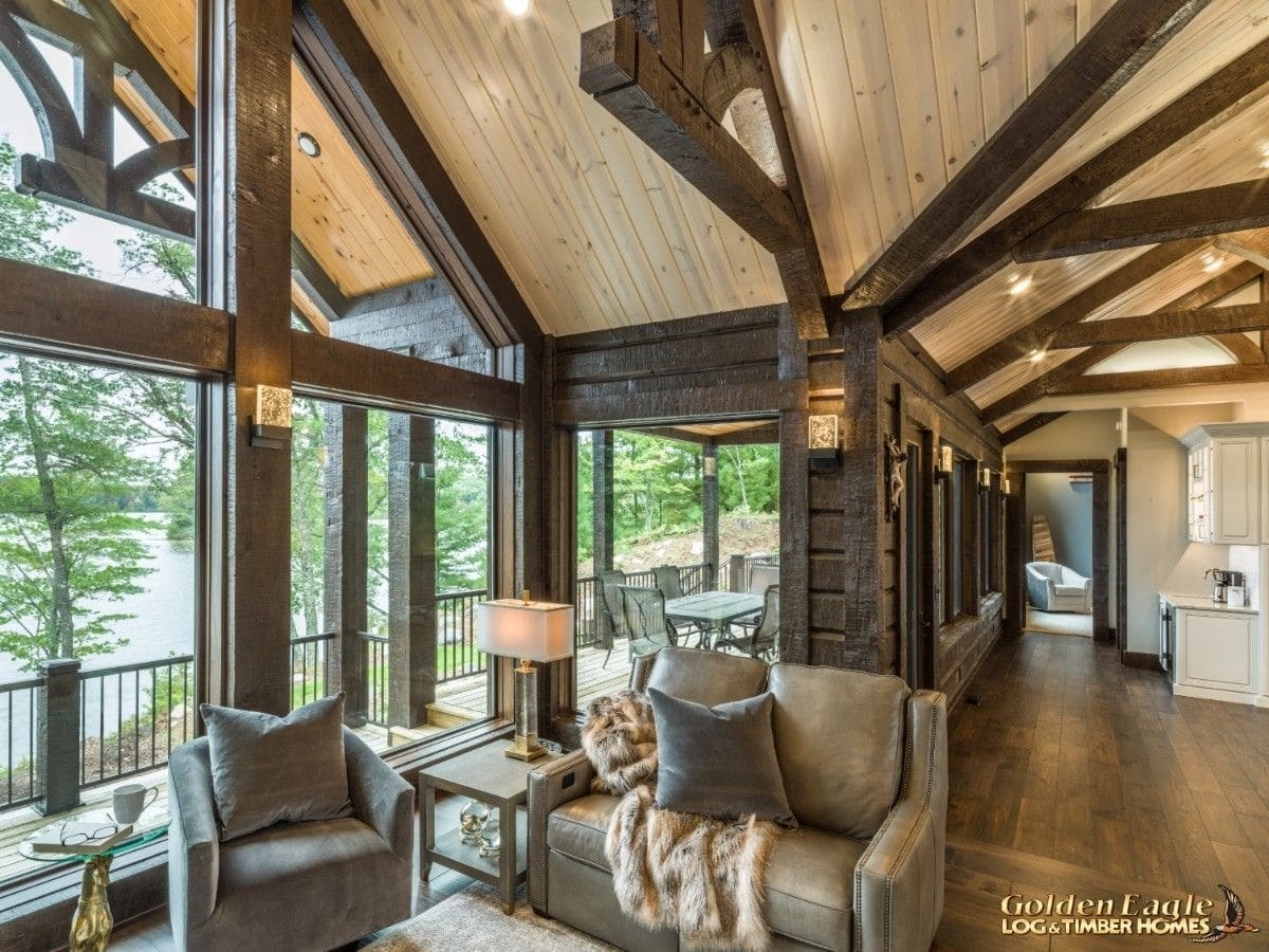 gray sofa against great room windows in log cabin