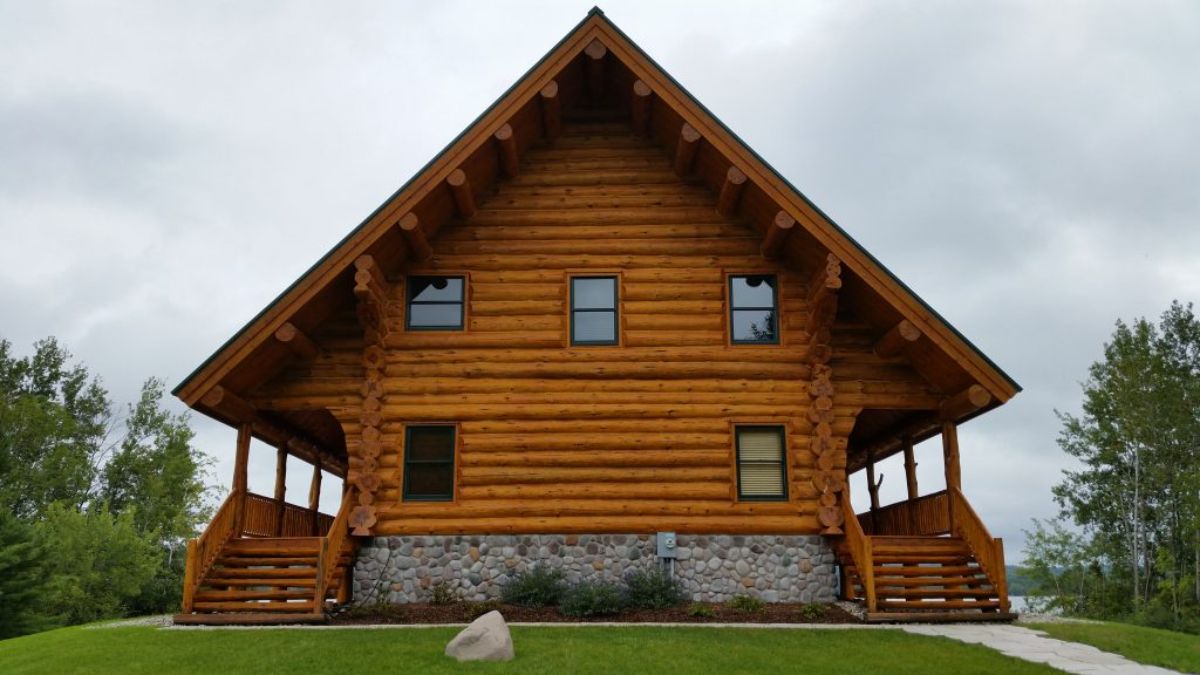 side of log cabin with 5 windows and stone foundation