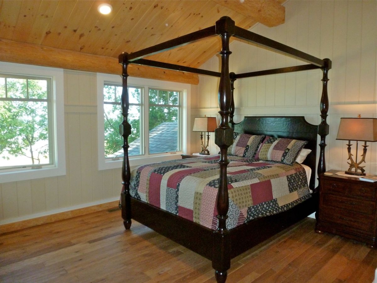 black four poster bed without canopy in log cabin bedroom with white walls