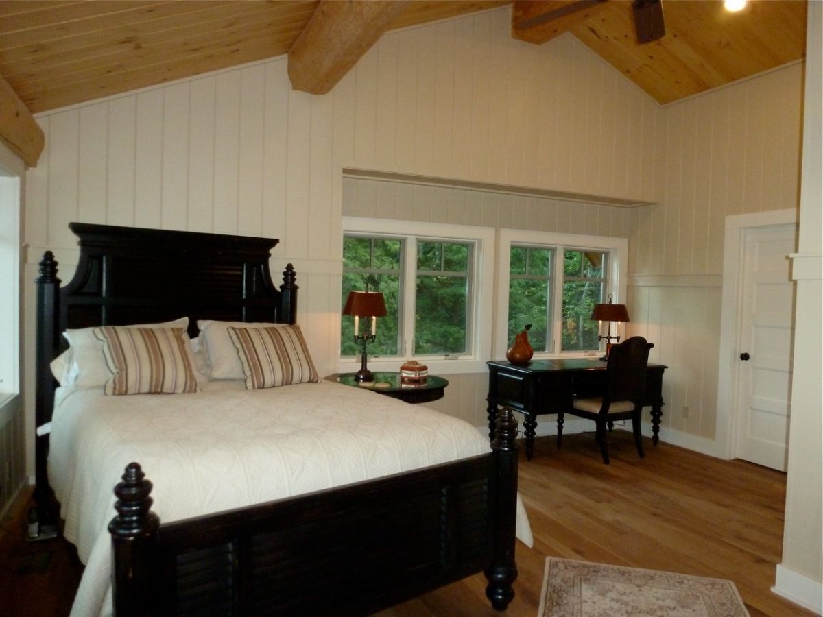 black furniture with white bedding and white shiplap walls on second floor of log cabin