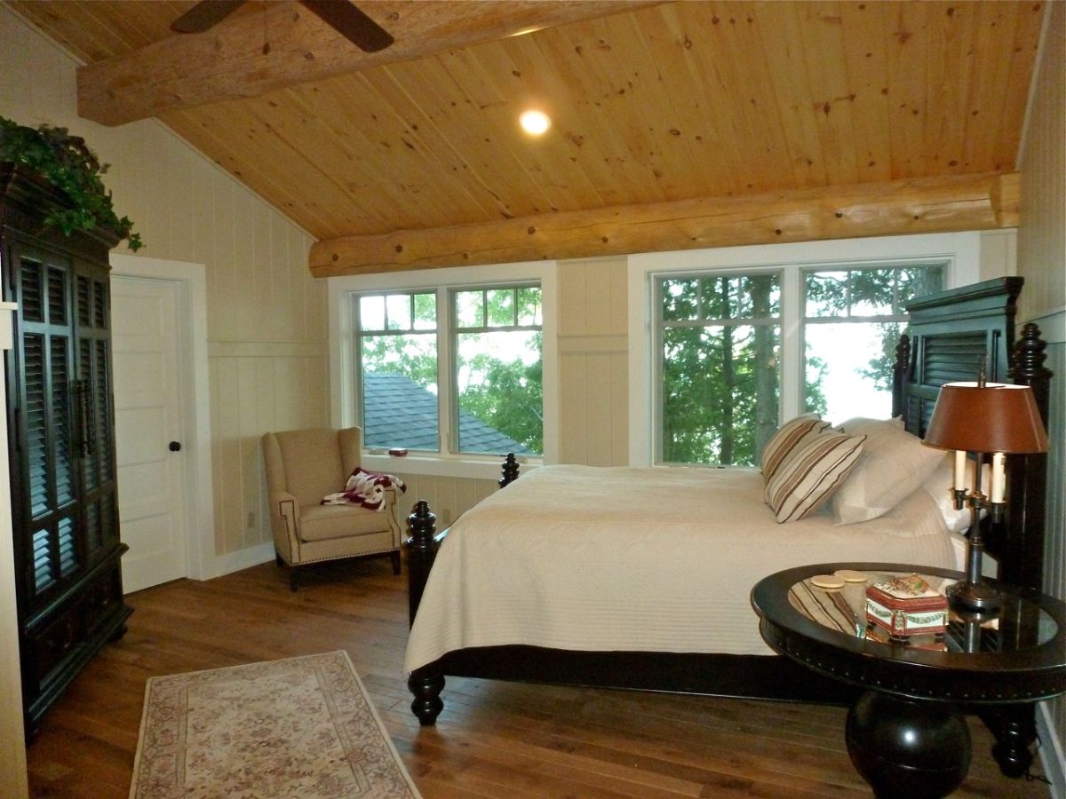 double windows on side of log cabin bedroom with black bed