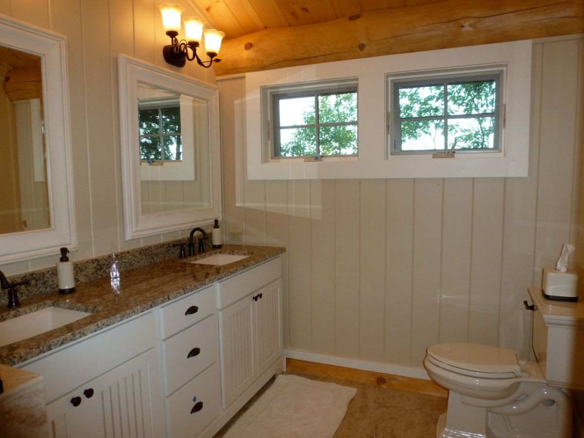 white shiplap walls below light wood ceilings in bathroom with dual sinks and white cabinets