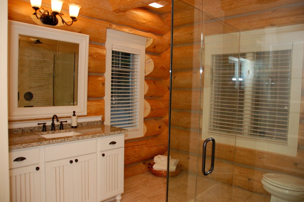 glass shower door across from white cabinet in log cabin