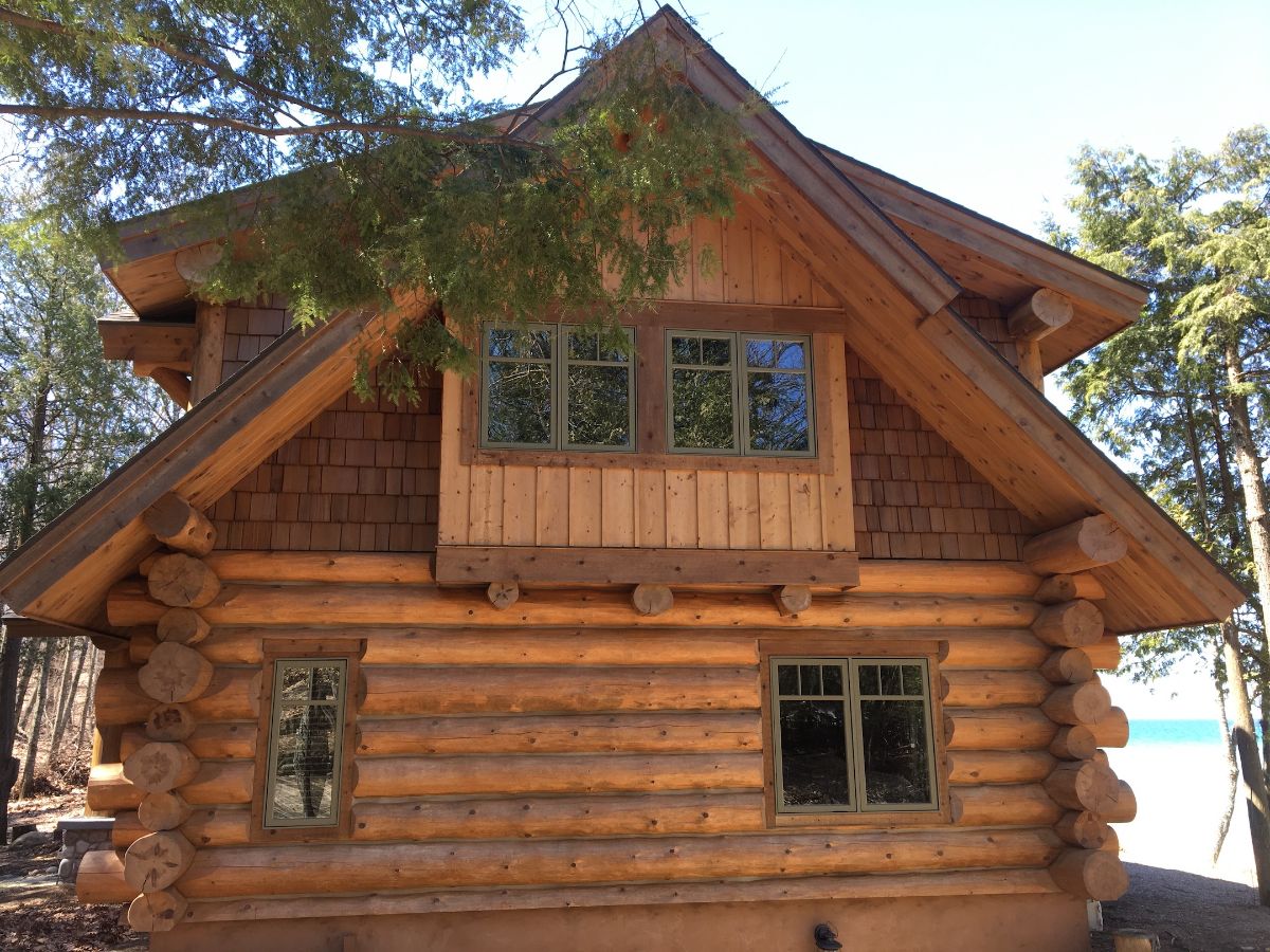 end of log cabin with two windows and second floor bay window