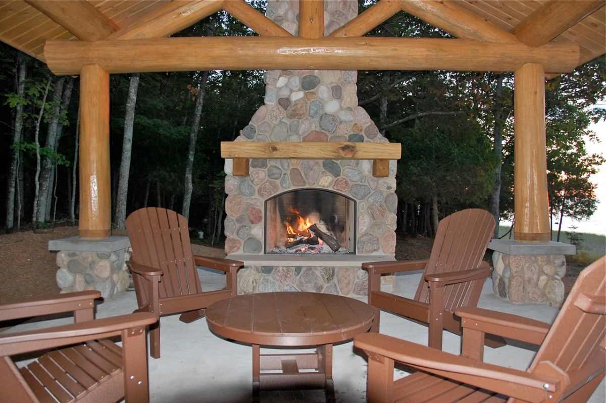 stone fireplace on patio with brown chairs and small round table