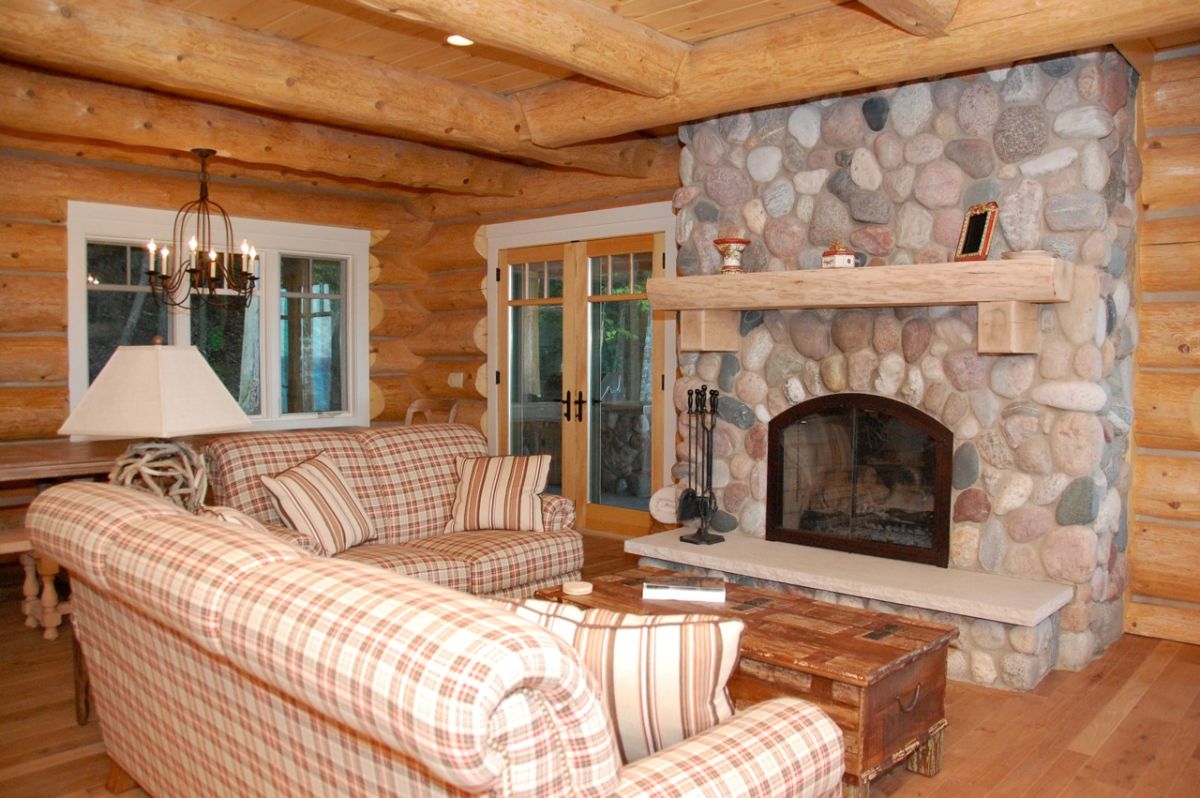 light brown plaid sofa in front of wood coffee table and stone fireplace