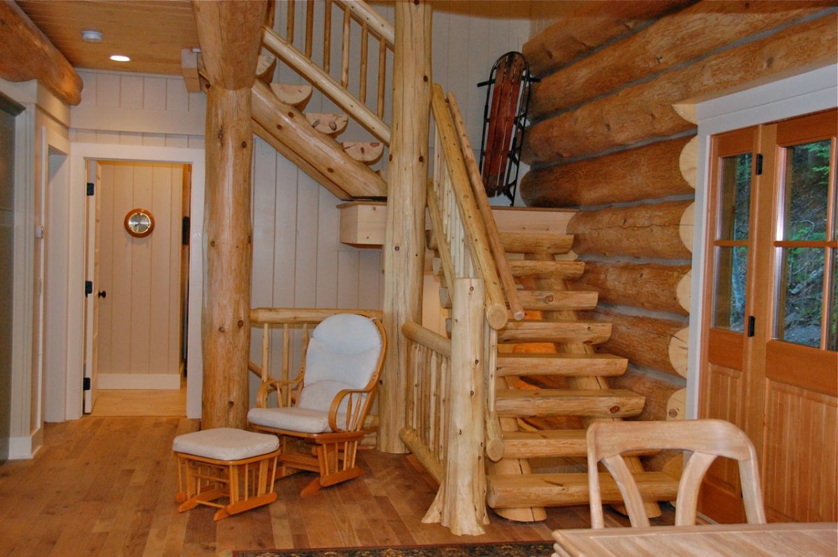 log stairs to second floor of light wood log cabin with whtie shiplap walls