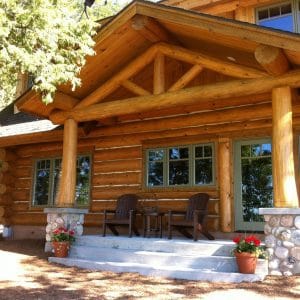 front of log cabin with awning over small concrete porch