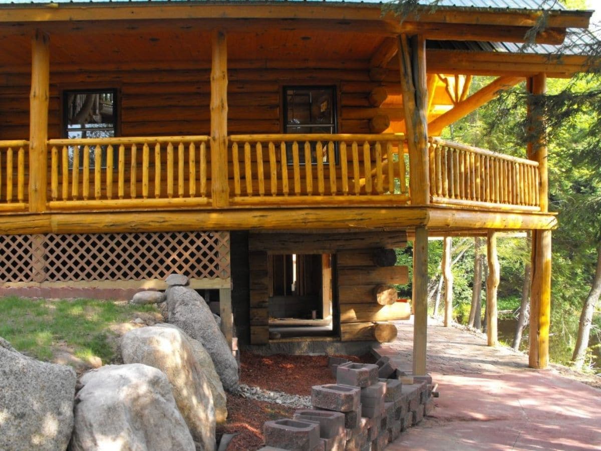 back side of log cabin showing walkout basement and balcony above bottom floor