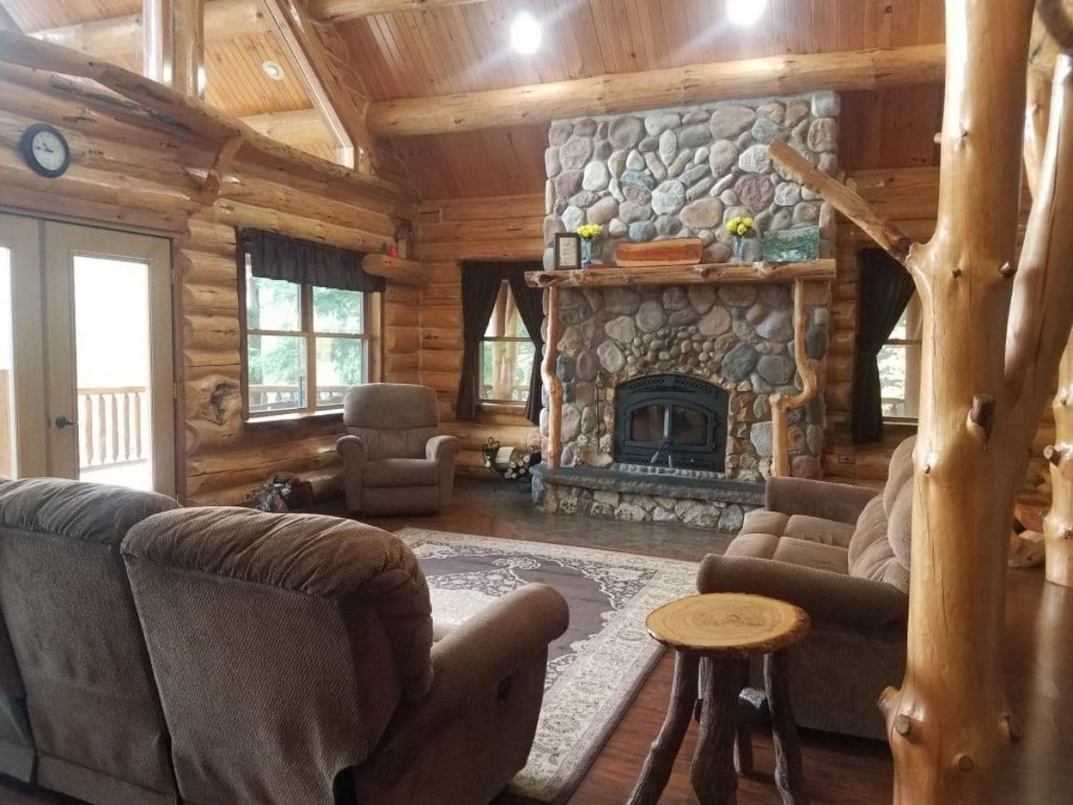 brown sofa with stone fireplace in background against log cabin walls