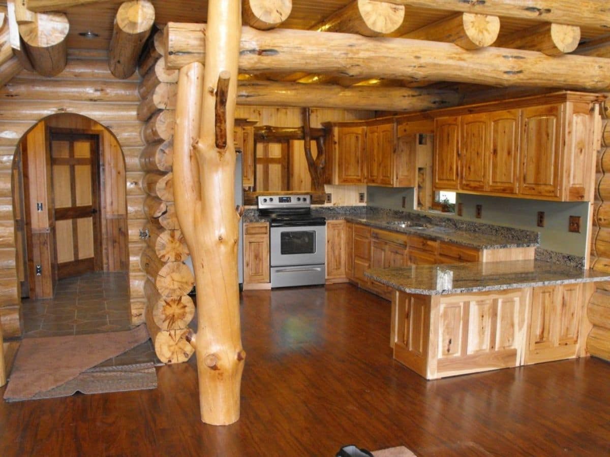 light wood cabinets with stainless steel appliances and log columns inside log cabin