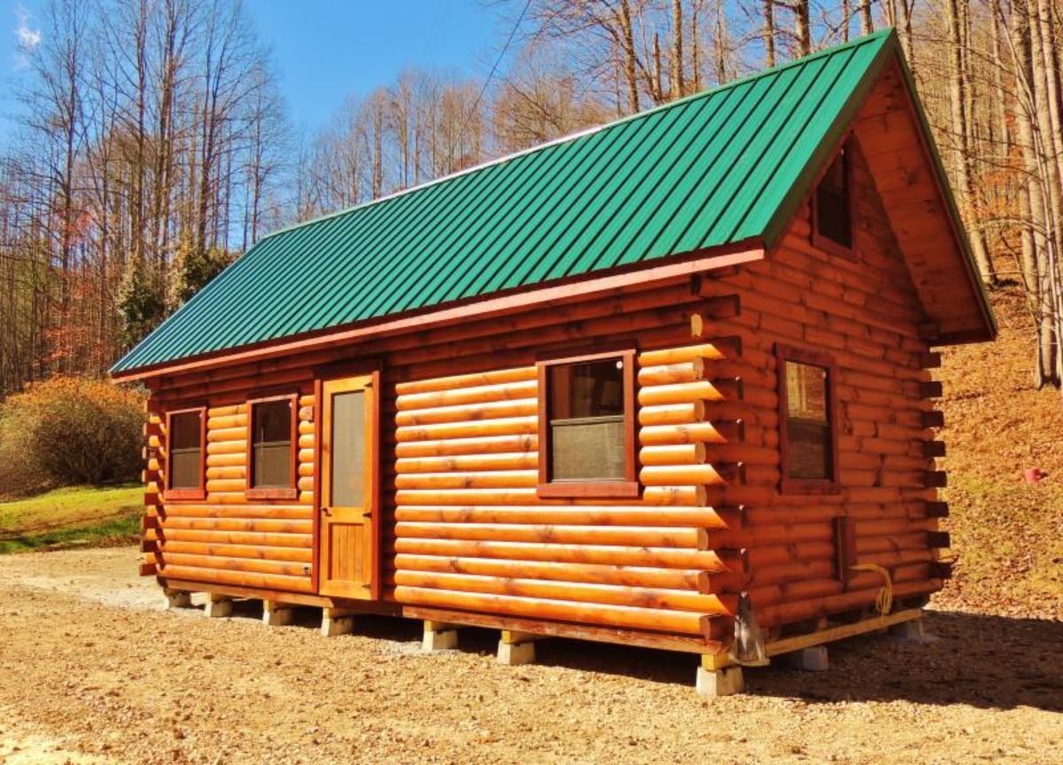 small log cabin with green roof and door on side