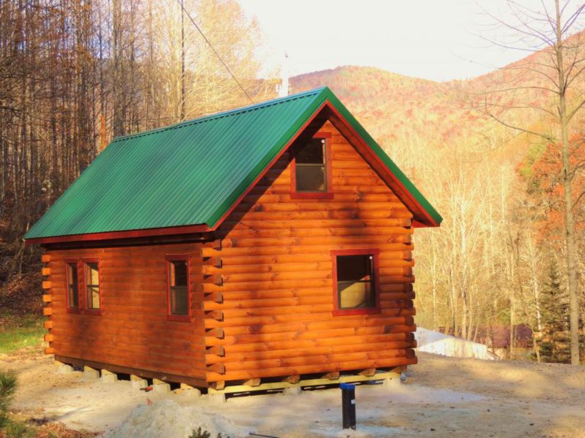 side of log cabin on hill with green roof