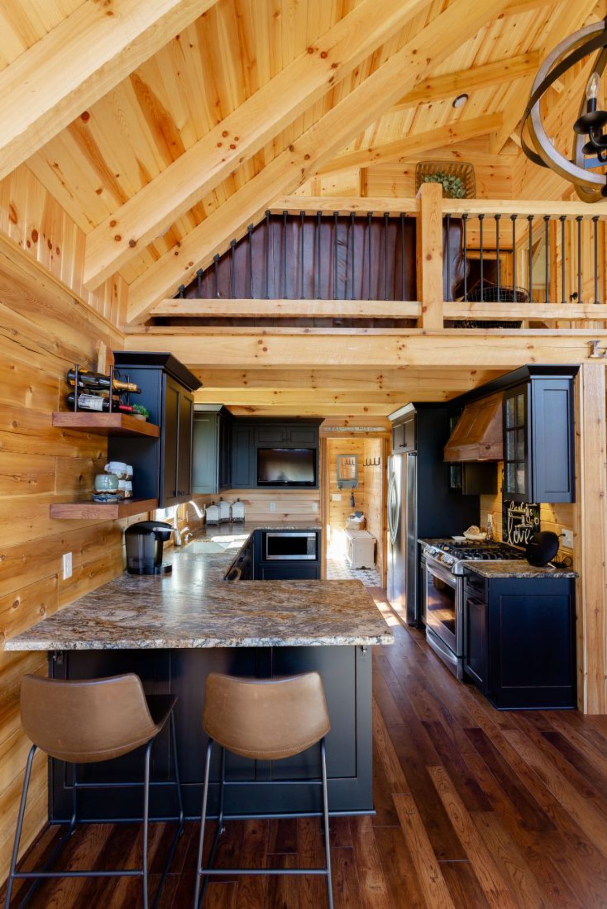 black cabinets and granite counters in kitchen of log cabin underneath loft space