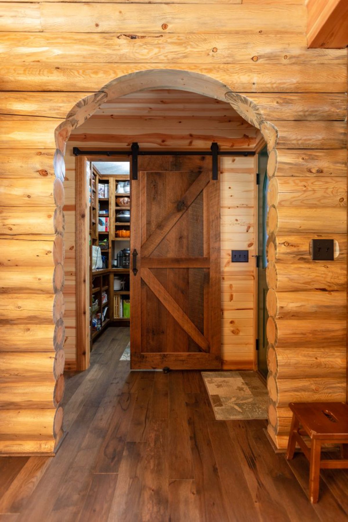 arch in hall of log cabin in front of barn door