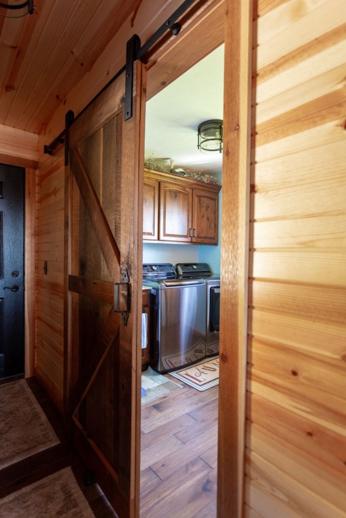 open barn door into laundry room with stainless steel laundry units