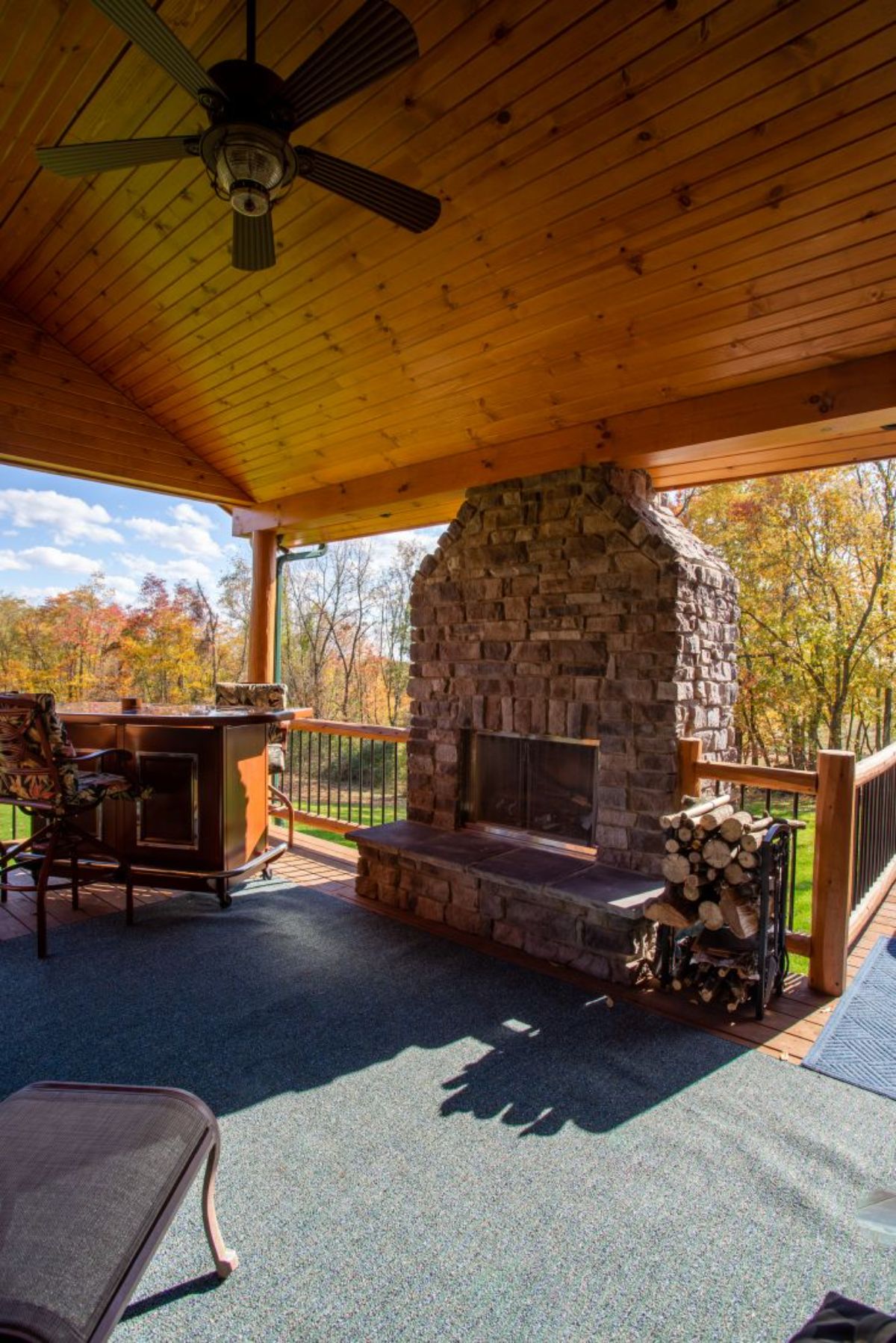 stone fireplace on edge of covered deck of log cabin