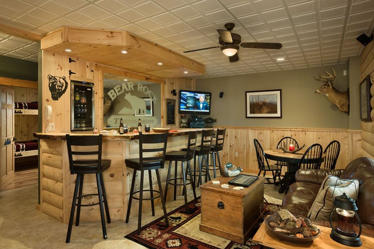 bar in basement living space with rug beneath coffee table behind stools