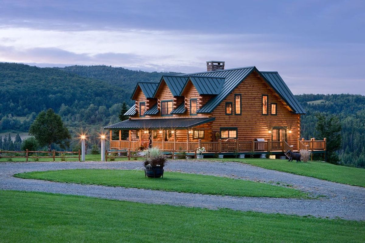 circle driveway in front of log cabin with long covered porch and green roof