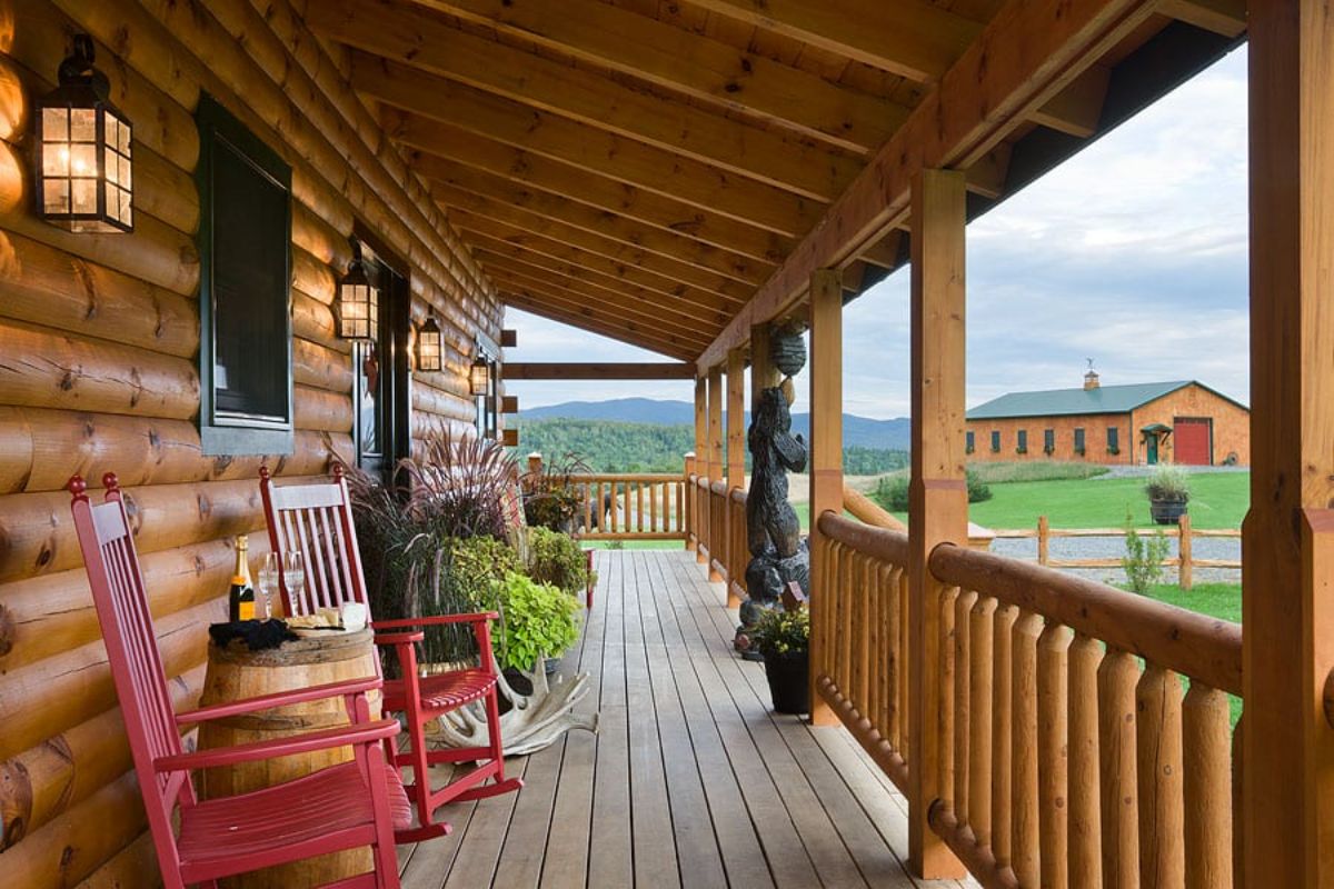 porch with red rocking chairs against wall and wood railing on front