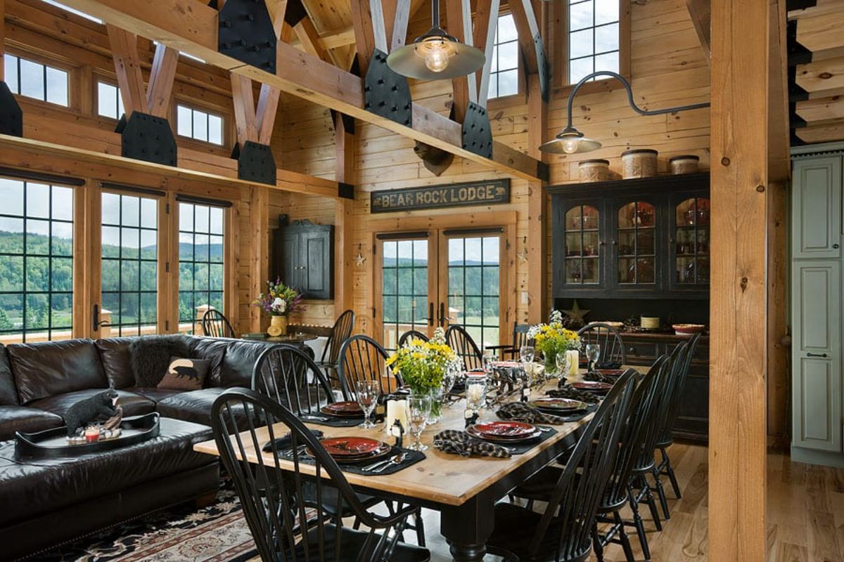 dining table with butcher block top and black chairs beneath open log beams