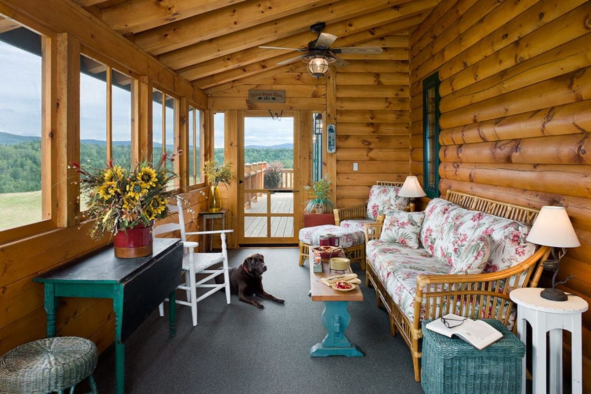 covered porch with wicker sofa against wall and teal end tables