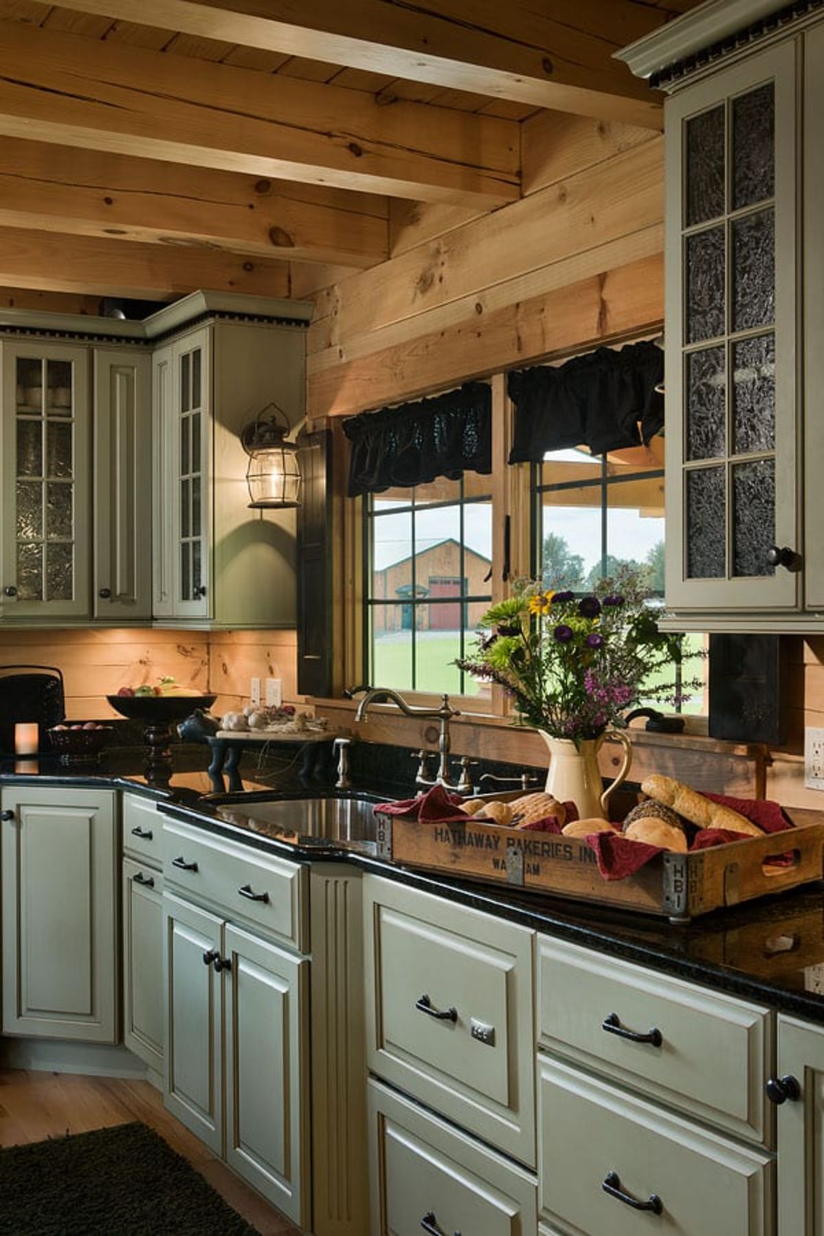 light green cabinets under black countertops in kitchen