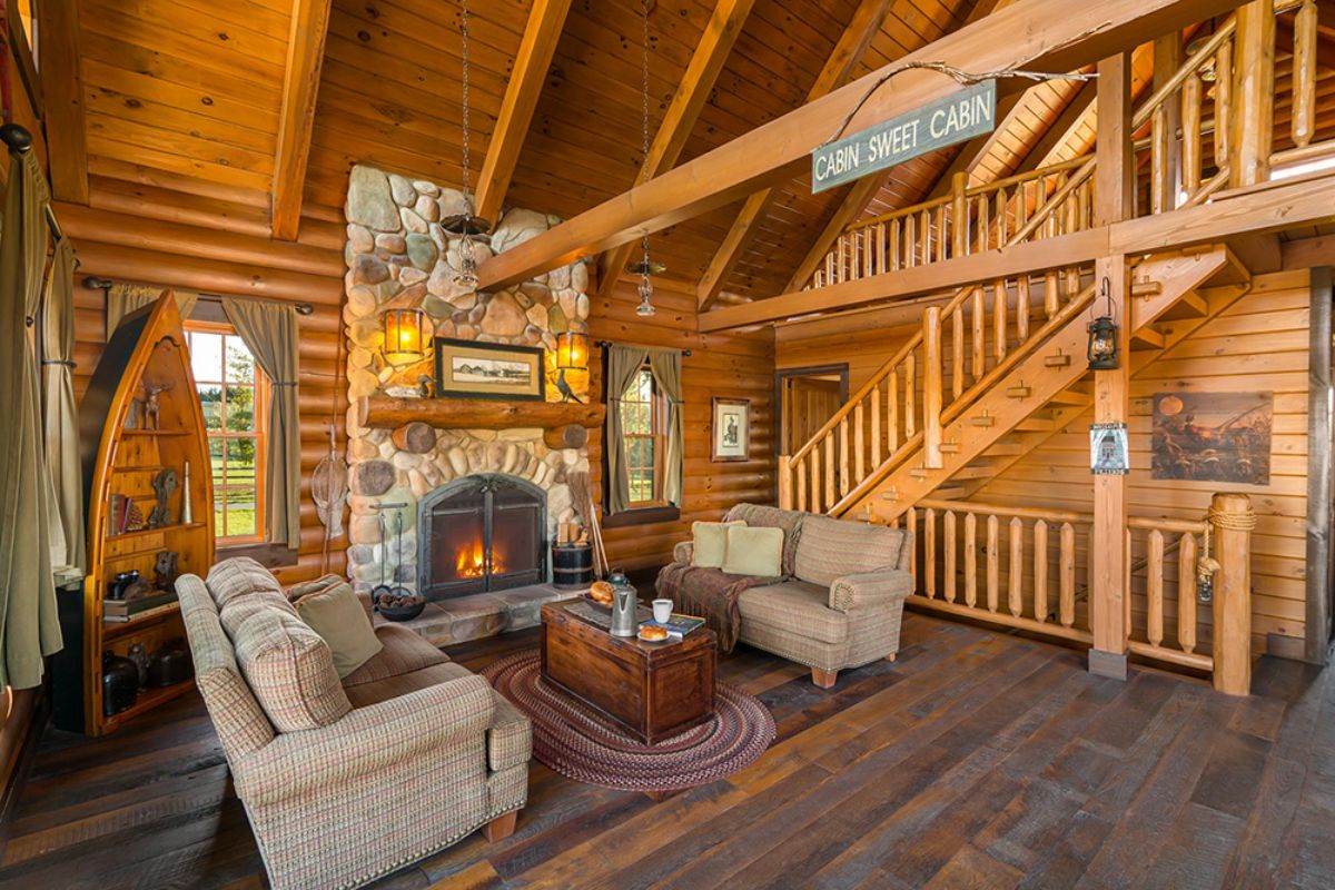 view into the living room of a log cabin with log stairs to top floor