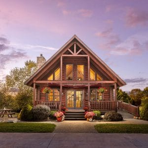 front of log cabin with wall of windows and purple sky background