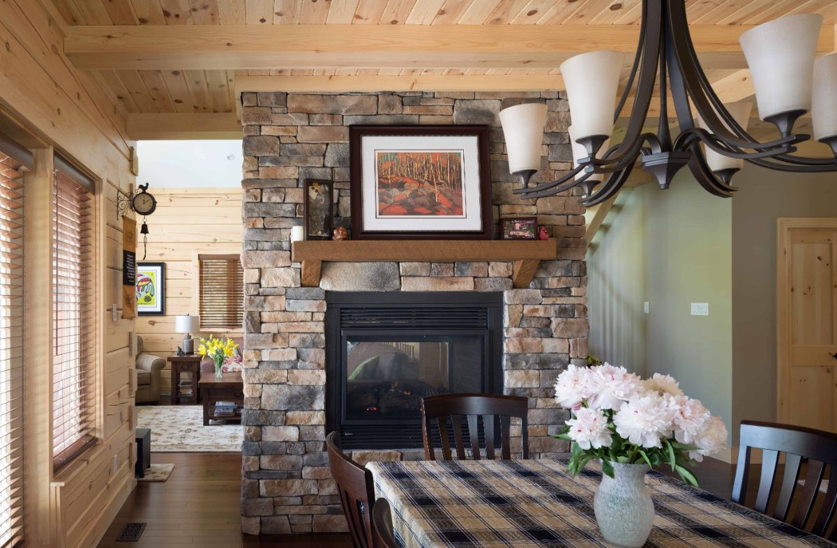 stone fireplace with wood mantle behind dining table with plaid tablecloth